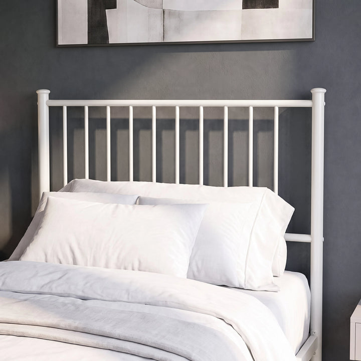 [White | Single] Metal bed close-up view of tall bar headboard with white pillows against a grey wall with abstract art.