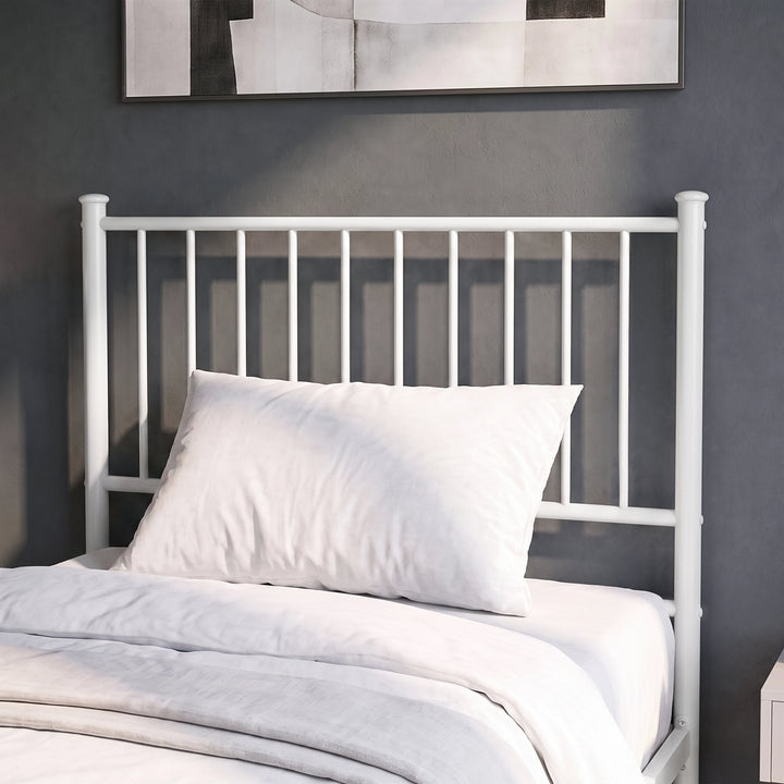 [White | Single] Metal bed close-up view of tall bar headboard with white pillows against a grey wall with abstract art.