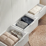 White wardrobe three drawer storage sections showing internal organisation and a stack of clothes