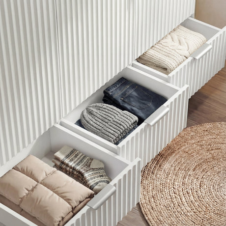 White wardrobe three drawer storage sections showing internal organisation and a stack of clothes
