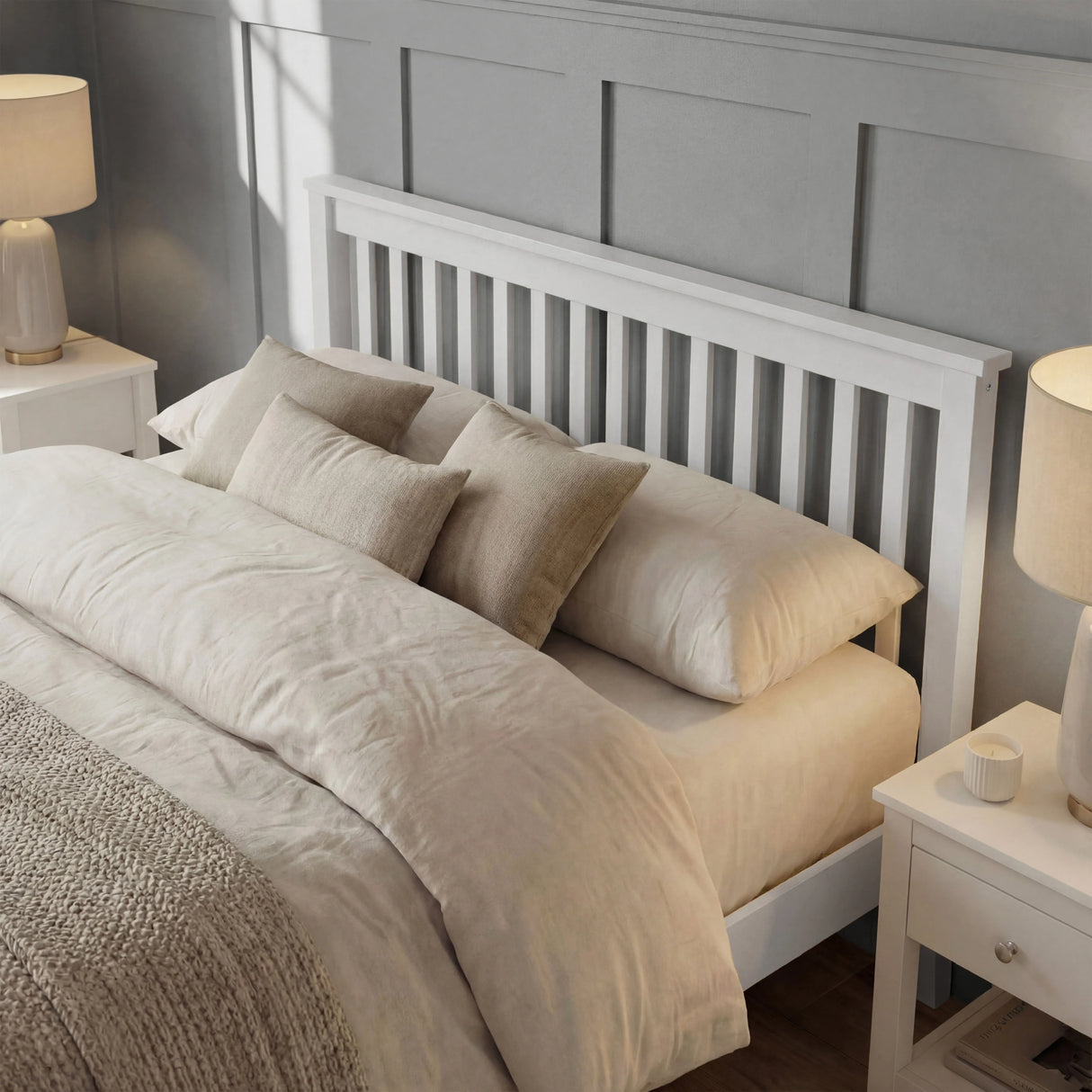 White double bed frame with slatted headboard, layered pillows, and neutral bedding arranged in a bedroom