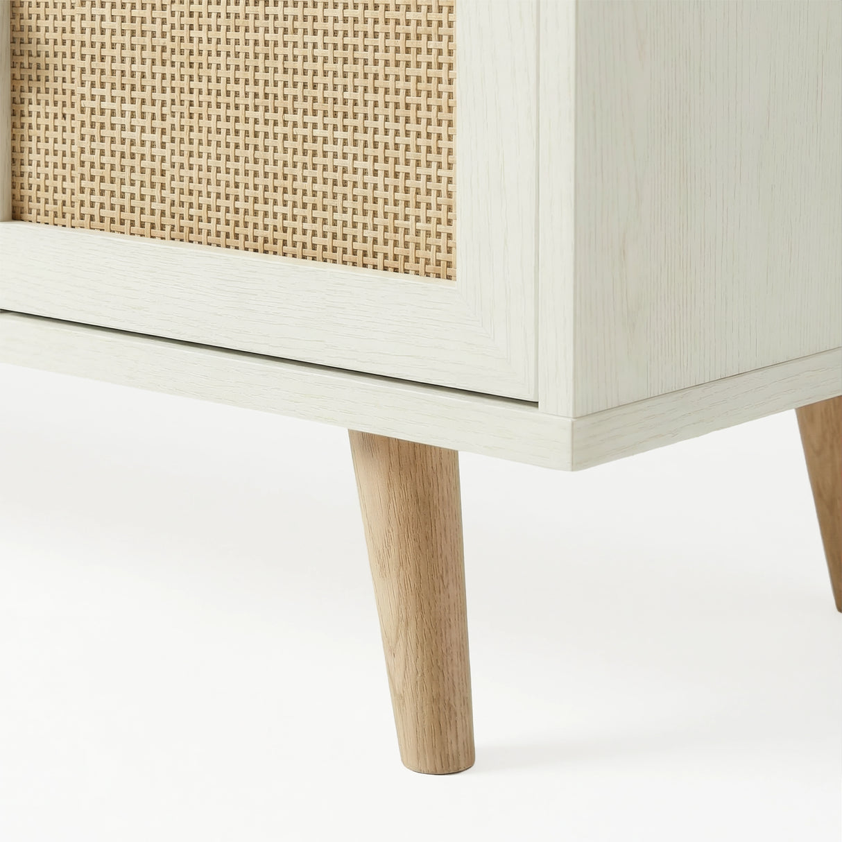 [White] Wovena close-up of natural oak tapered leg and rattan cane panel edge detail against a white background