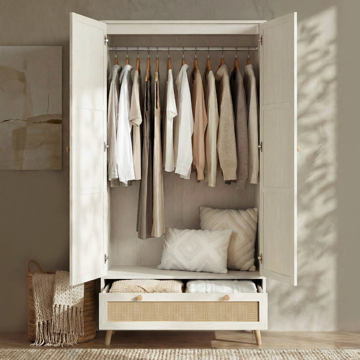 [White] Wovena rattan wardrobe with both doors open revealing chrome hanging rail and beige knit garments above drawer