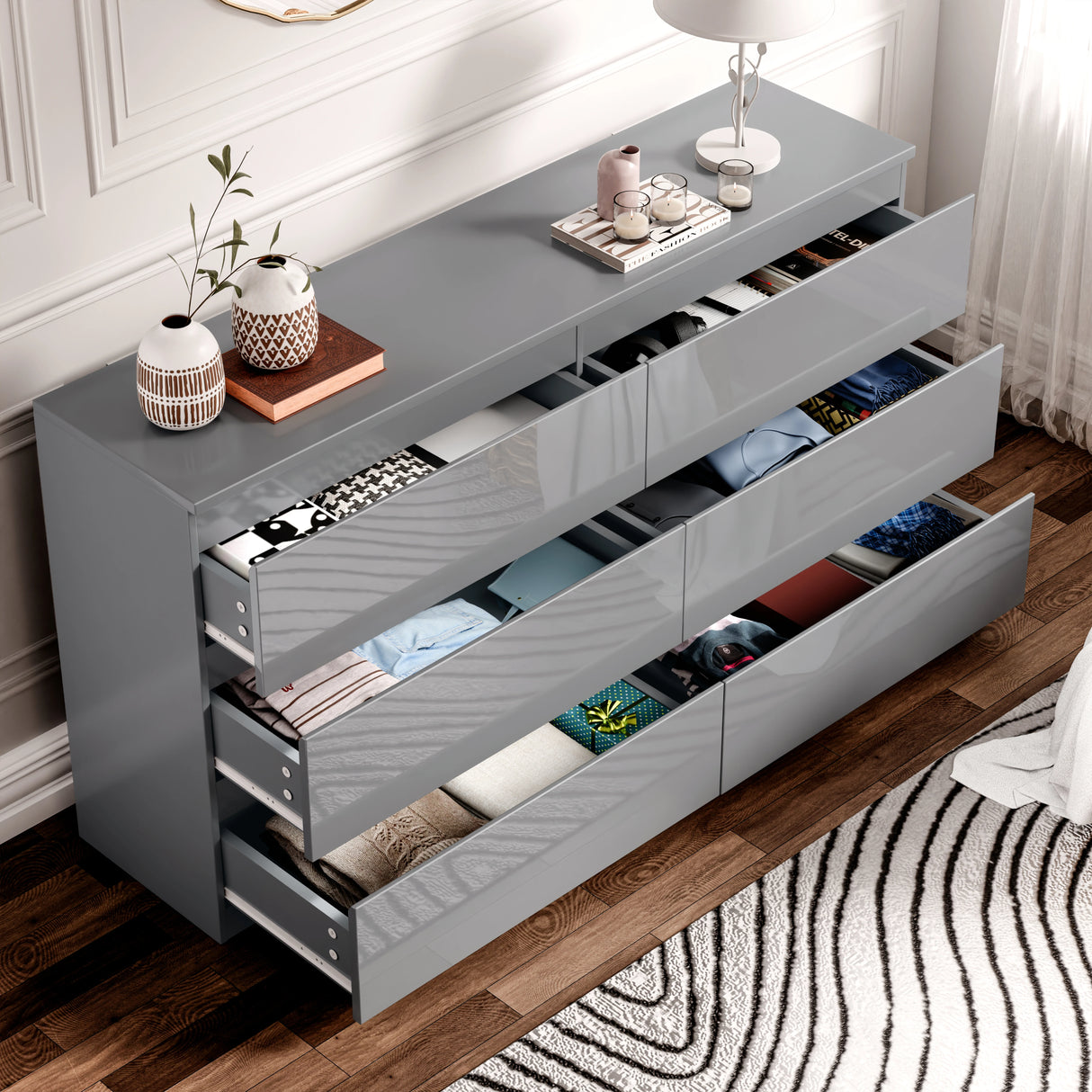 Gray dresser with open drawers containing clothes in a room setting.