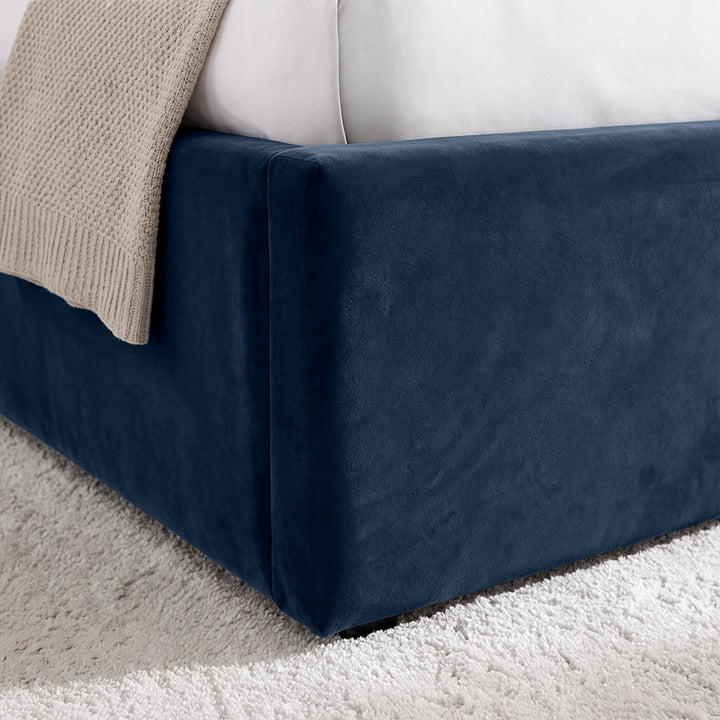 [Blue | King] Close-up of padded footboard corner showing plush fabric and Elevated bed base detail