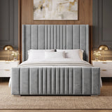 [King | Light Grey] upholstered bed with a tall vertically channel-tufted headboard and matching footboard, styled in a contemporary bedroom with white bedding, two white nightstands, gold table lamps, and a wood-panelled wall.