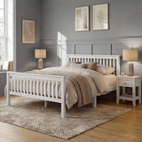 White wooden double bed frame with slatted headboard and footboard, with neutral bedding in a softly styled bedroom