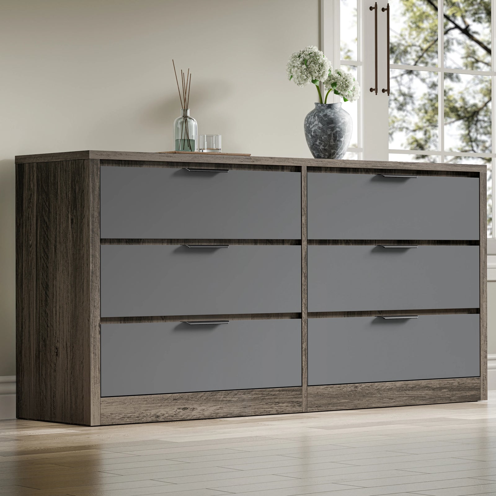 Large chest of drawers in a two-tone oak grey finish, showing six drawers, placed in a room near a window