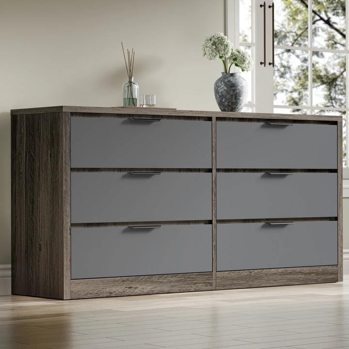 Large chest of drawers in a two-tone oak grey finish, showing six drawers, placed in a room near a window