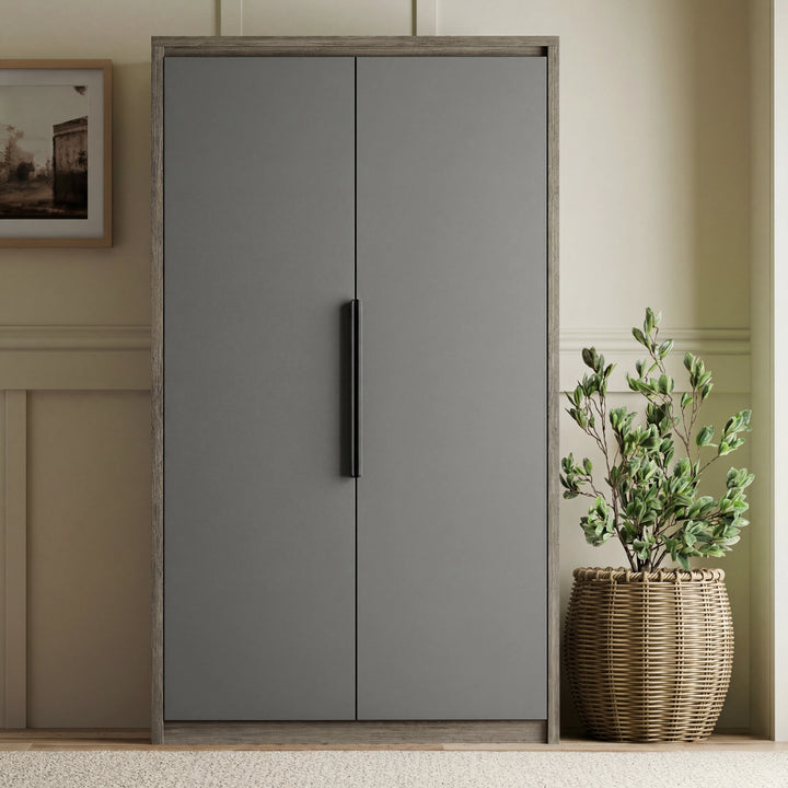 [Wooden Grey+Grey] Closed Skova wardrobe wooden grey frame and matt grey doors against panelled wall with potted plant beside