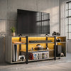 [Wooden Grey] Industrial LED TV Stand with Storage in a concrete loft setting with amber LED underlighting, open shelves holding a console, VR headset and game cases