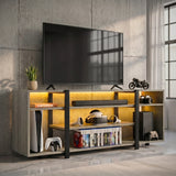 [Wooden Grey] Industrial LED TV Stand with Storage in a concrete loft setting with amber LED underlighting, open shelves holding a console, VR headset and game cases