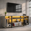[Wooden Grey] Zelumi TV stand angled view in a concrete-wall room with warm yellow LED shelves, consoles, VR headset, game cases and plant on top surface