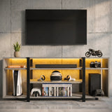 [Wooden Grey] Zelumi TV stand front-facing against a concrete wall with warm yellow LED shelves, consoles, VR headset, game cases and decorative items on top