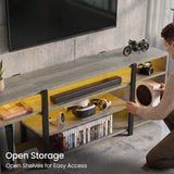 [Wooden Grey] Zelumi TV stand showing open shelf storage with warm yellow LED lighting and person placing gaming console into the right side compartment