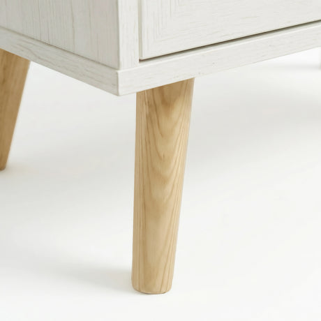 [White] Wovena chest detail showing tapered solid wood leg with white painted finish and natural wood grain contrast