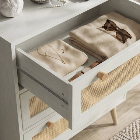 [White] Wovena chest of 3 drawers detail showing open top drawer with folded clothing, necklace, watch and sunglasses inside