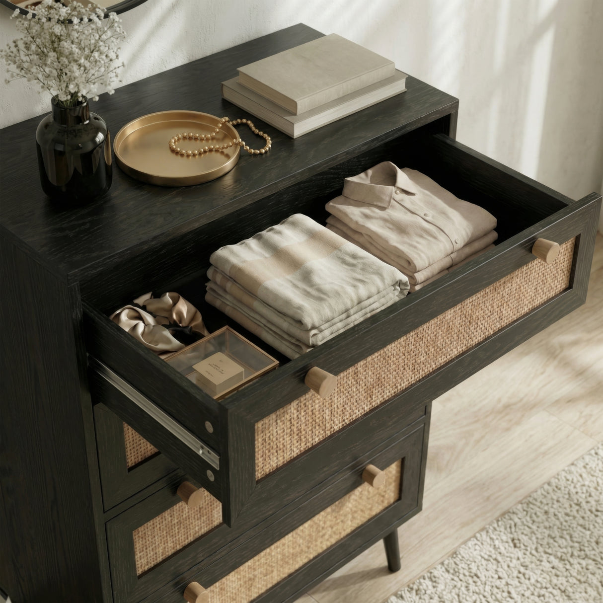 [Black] Wovena 4 drawer chest top drawer open with organised clothing beside books and dried flowers