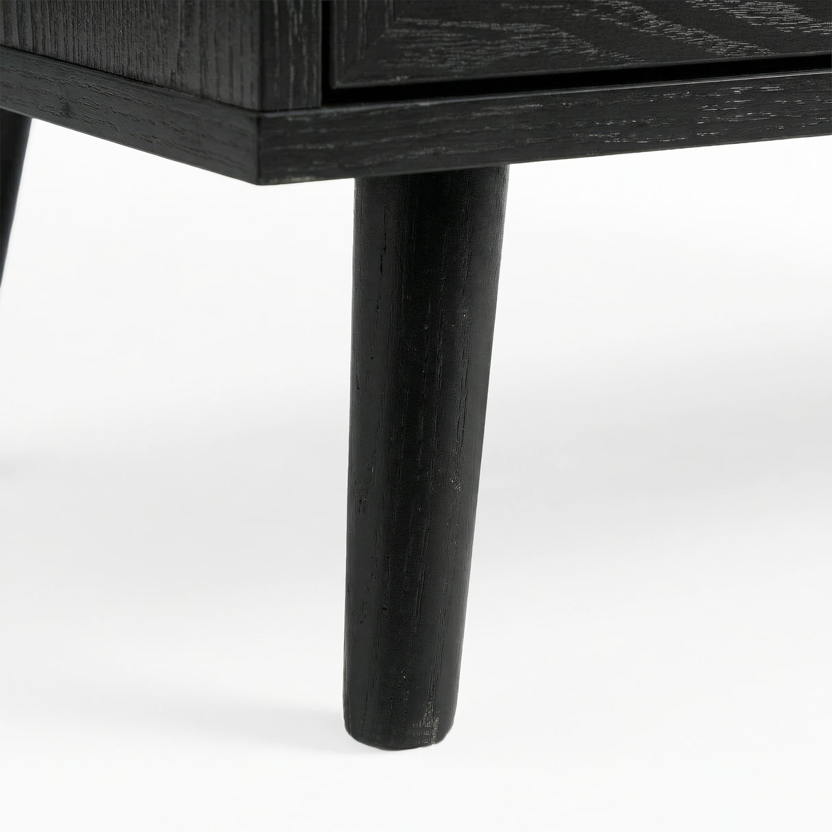[Black] Wovena close-up of a solid tapered black leg of chest showing the wood grain texture and painted finish detail