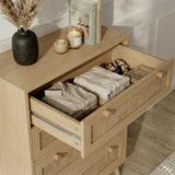 [Oak] Wovena chest top drawer pulled open in a styled room, showing folded clothing inside with candles and books on top