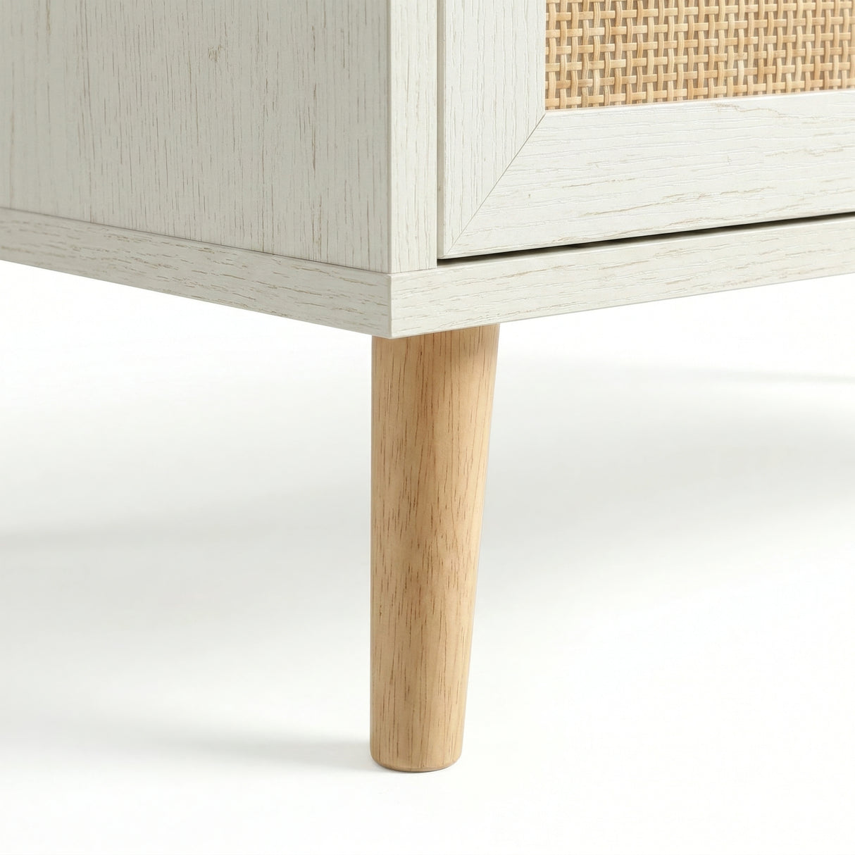[White] Wovena rattan chest leg close-up, tapered natural pine leg meeting white carcass corner