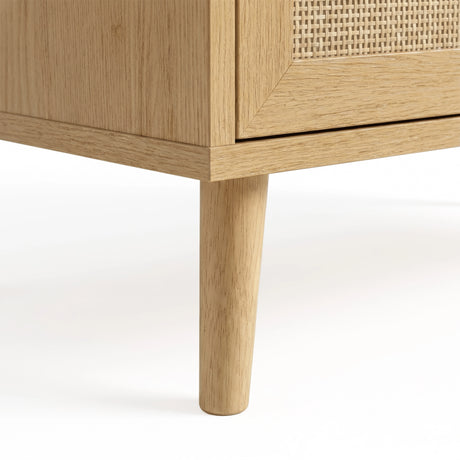 [Oak Effect] Tapered wooden leg of Wovena rattan chest of drawers viewed at the corner beneath rattan bottom drawer