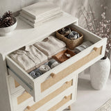 [White] Close view of Wovena rattan tallboy chest top drawer extended, books and pine cone resting on surface