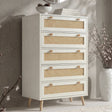 [White] Wovena rattan tallboy chest with five cane drawers angled view, ceramic bowl and round mirror styled on top