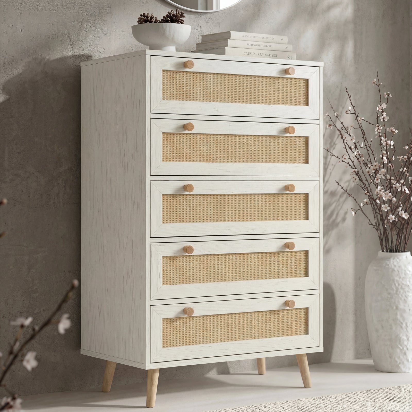 [White] Wovena rattan tallboy chest with five cane drawers angled view, ceramic bowl and round mirror styled on top