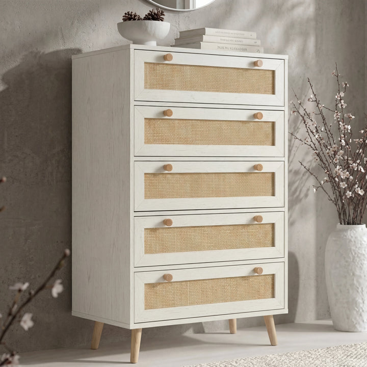 [White] Wovena rattan tallboy chest with five cane drawers angled view, ceramic bowl and round mirror styled on top