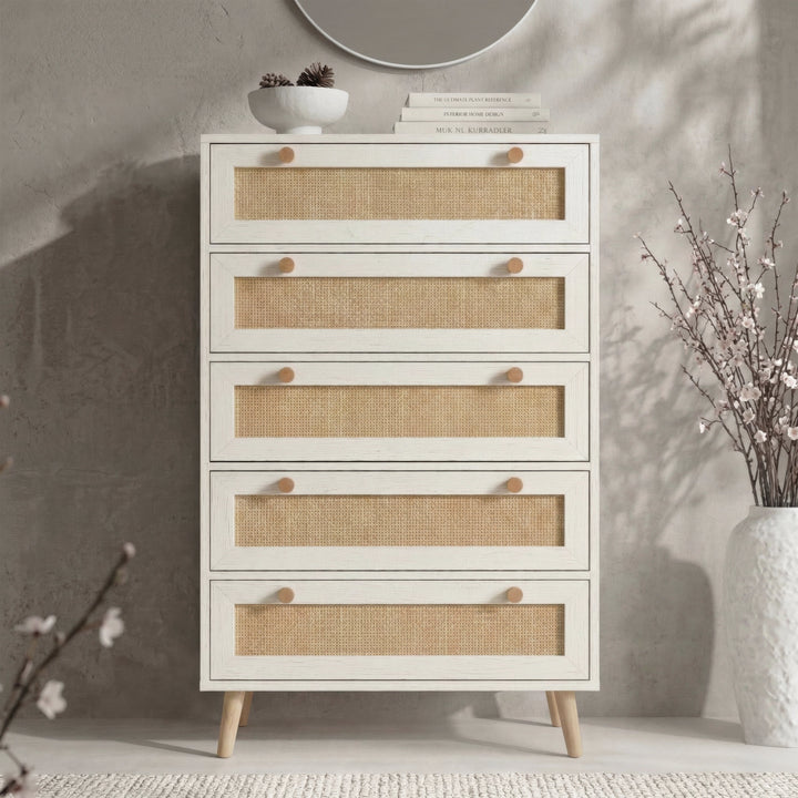 [White] Wovena rattan tallboy chest front view with round wall mirror, berry vase and stacked books on top