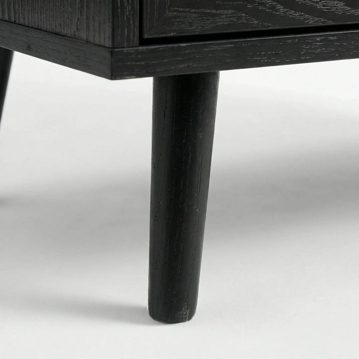 [Black] Detail of Wovena rattan bedside angled leg attached to cabinet, dark grain on leg and body