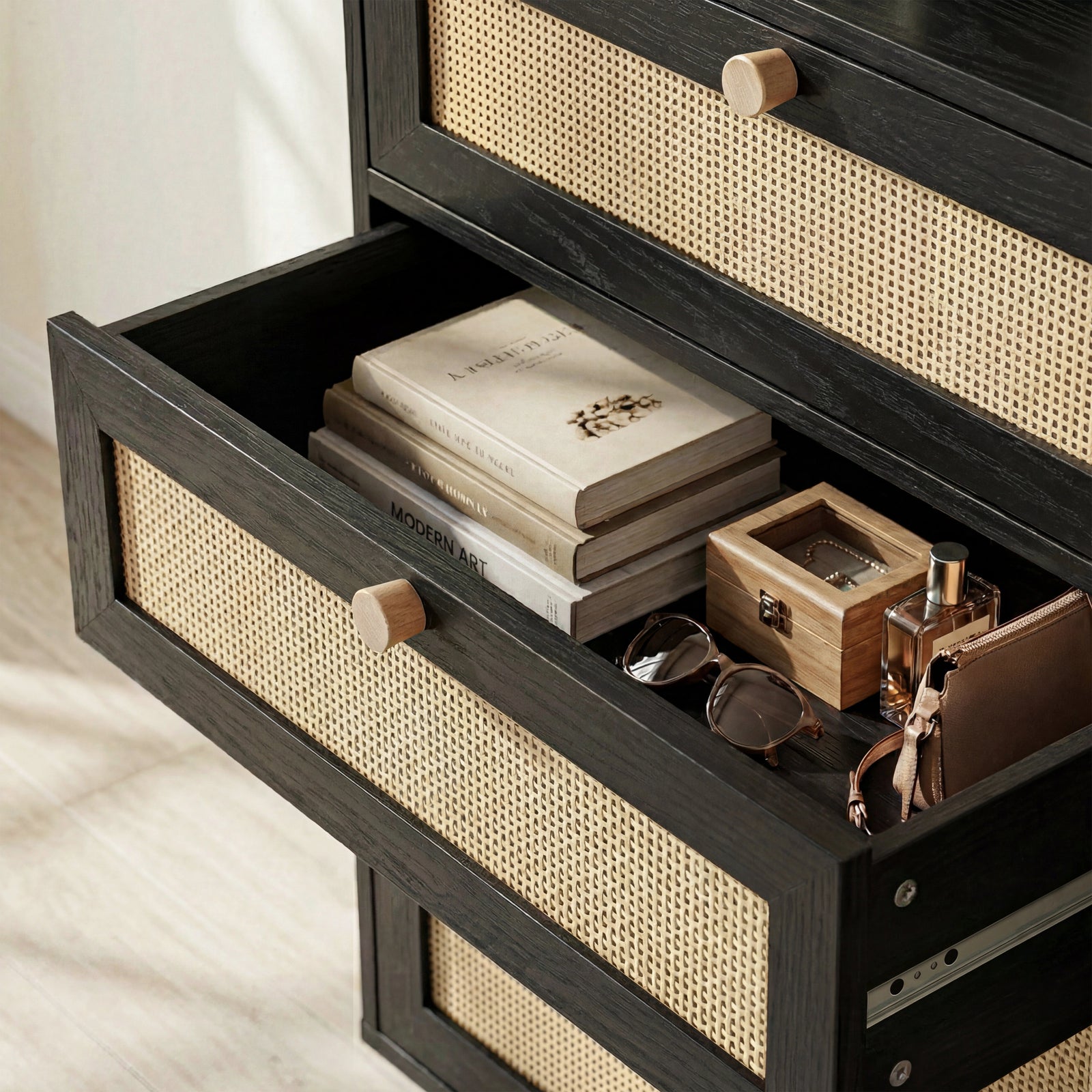 [Black] Wovena rattan chest open drawer interior shown with two books, wooden box and glasses on cane-front base