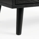 [Black] Close-up of black-painted tapered leg supporting Wovena rattan chest, wood grain visible through finish