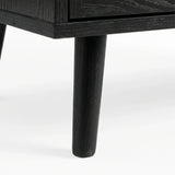 [Black] Close-up of black-painted tapered leg supporting Wovena rattan chest, wood grain visible through finish
