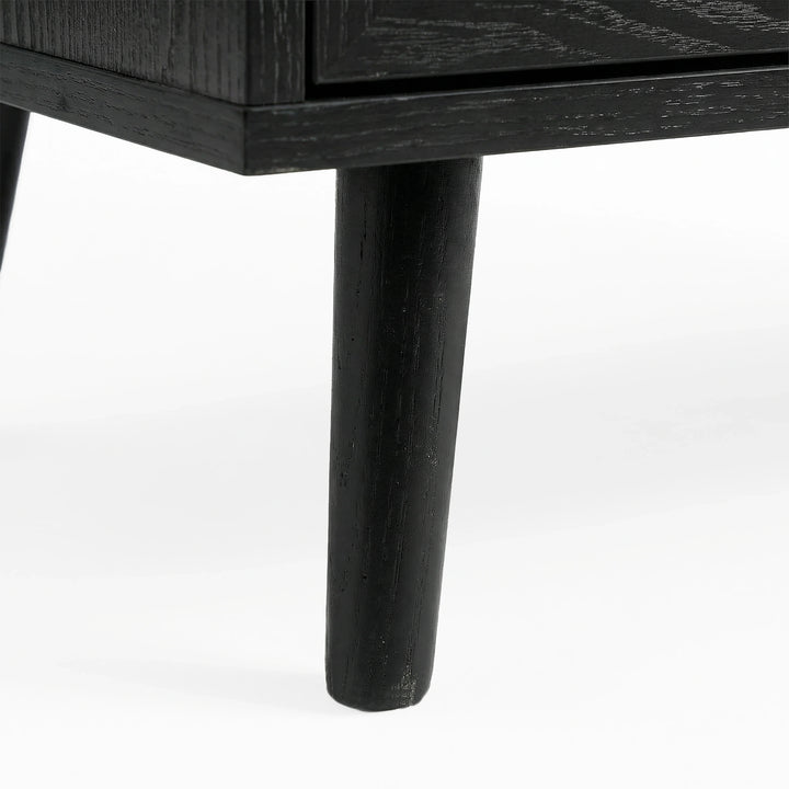 [Black] Wovena rattan chest tapered leg detail at base corner of the black painted frame