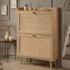[Oak] Wovena Rattan Oak 2 Door Shoe Storage Cabinet angled in grey hallway with staircase, black side table, peach vase, and succulent and reed diffuser on top shelf