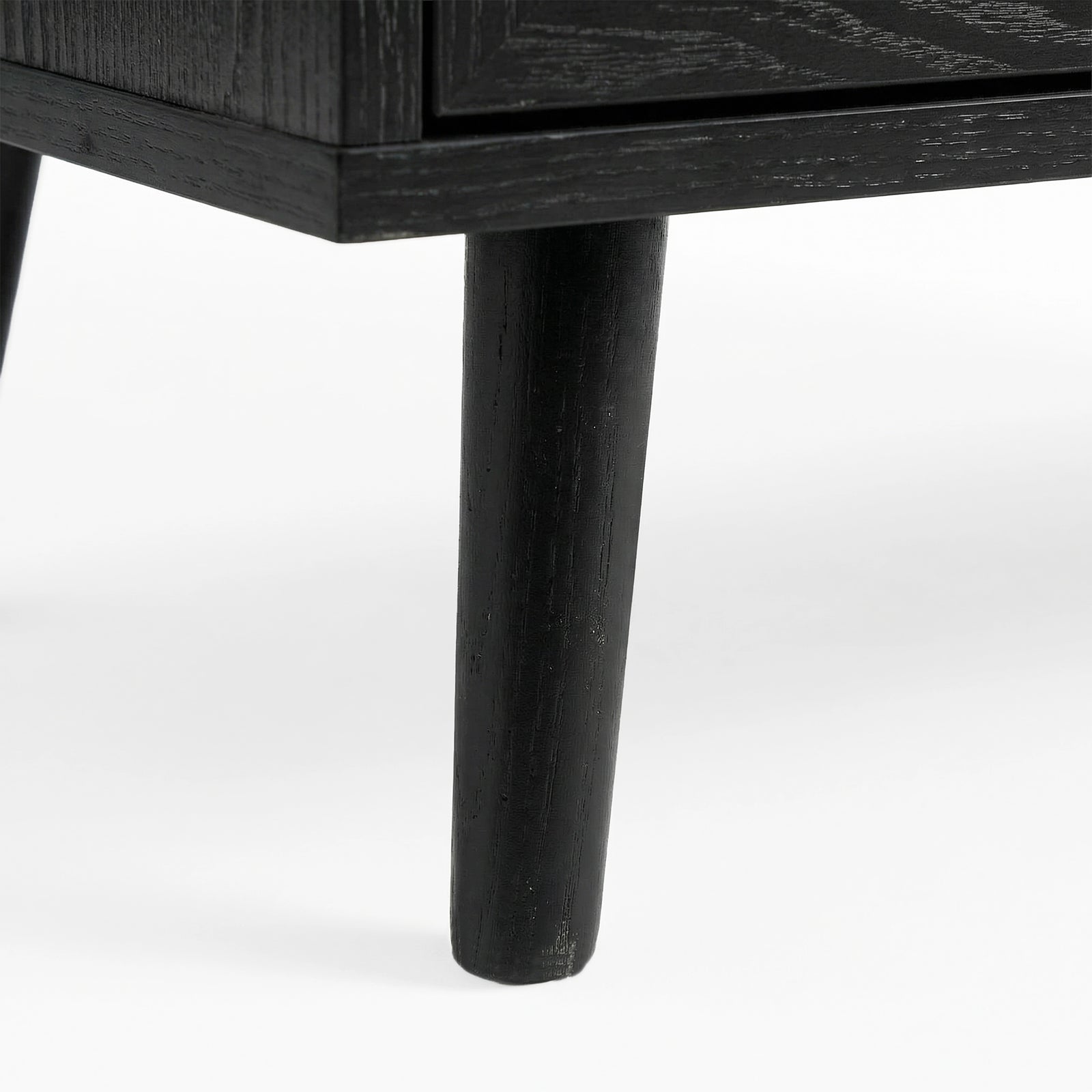 [Black] Tapered wooden leg detail on Wovena rattan wardrobe, painted black and angled outward from corner