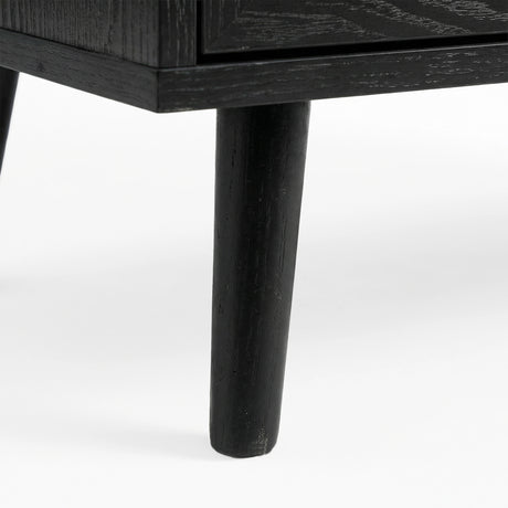 [Black] Wovena furniture leg detail displaying solid wood construction and mid-century tapered profile against plain floor