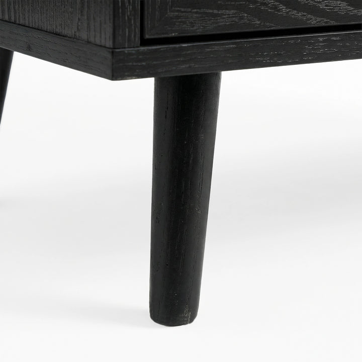 [Black] Tapered wooden leg detail on Wovena rattan wardrobe, painted black and angled outward from corner