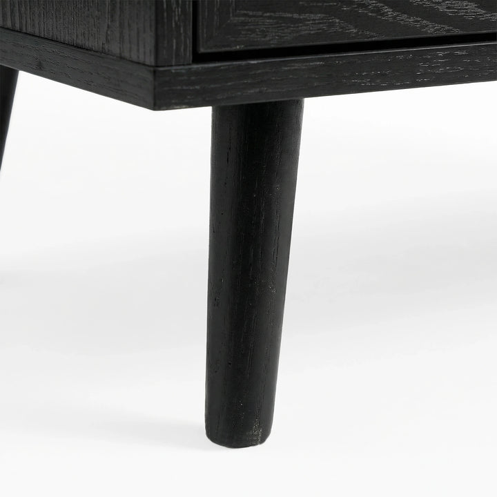 [Black] Tapered wooden leg detail on Wovena rattan wardrobe, painted black and angled outward from corner