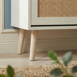 [White] Wovena Rattan White 2 Door Shoe Storage Cabinet base close-up showing tapered natural wood legs on herringbone floor with rattan door panel detail