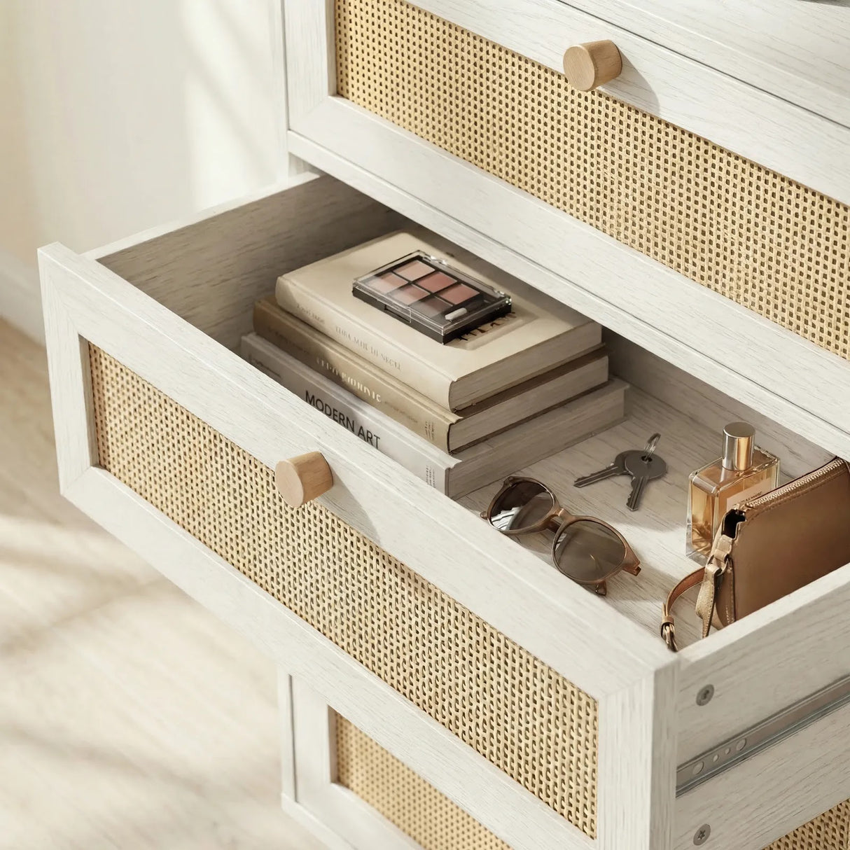 [White] Wovena rattan chest from above-angle showing drawers extended on smooth runners with folded contents