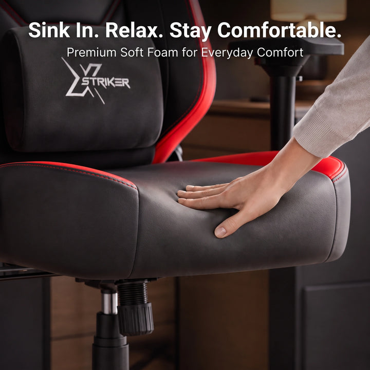 [Black + Red] A close-up of a black and red gaming chair with a hand pressing down on the padded seat to demonstrate its soft foam comfort. 