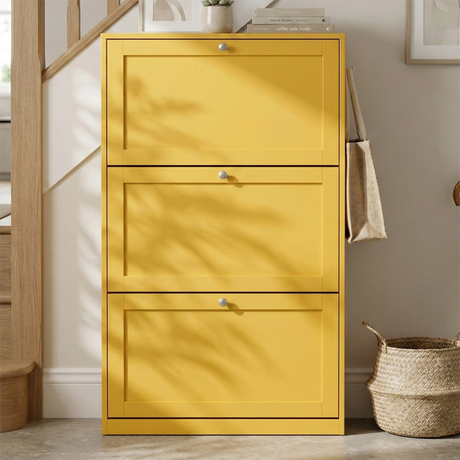 [Yellow]  Shaker Shoe Cabinet closed three-door flip-front unit in hallway setting with woven basket and staircase in background