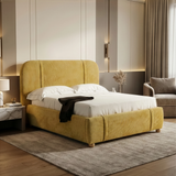 Yellow fabric king-size bed frame positioned at an angle in a softly lit bedroom